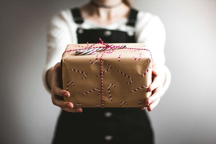 Une femme donnant un cadeau à une personne hors champ